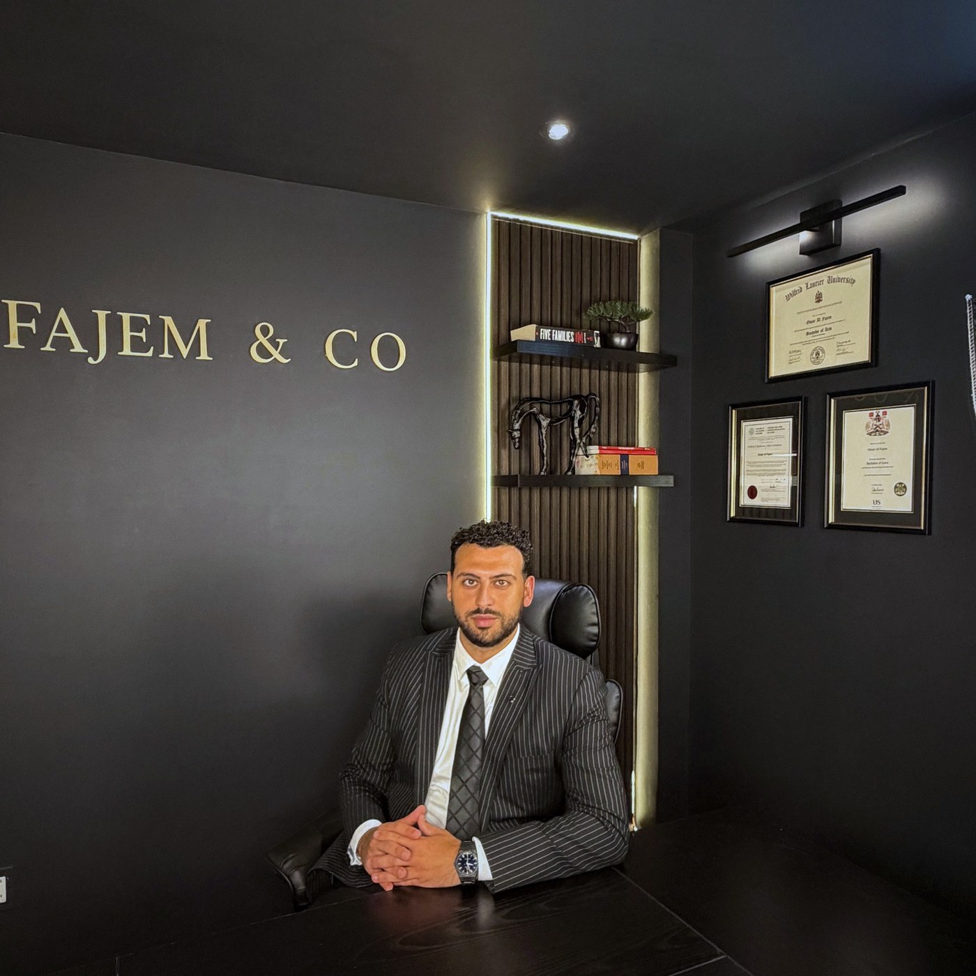 Omar Fajem at the Fajem & Co. office, with framed academic and legal credentials